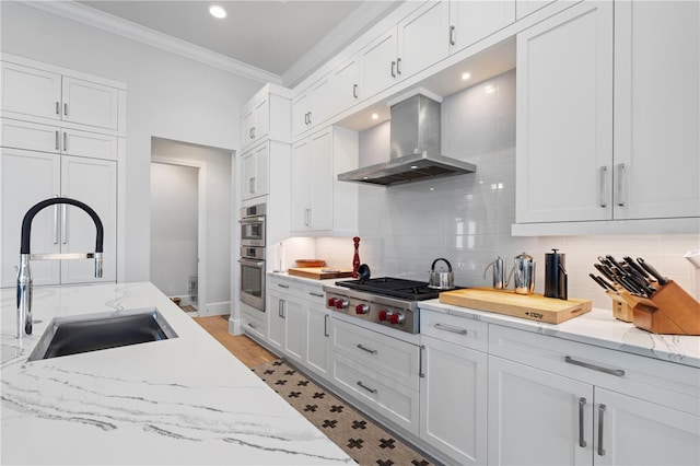 kitchen featuring white cabinets, stainless steel appliances, sink, wall chimney exhaust hood, and tasteful backsplash