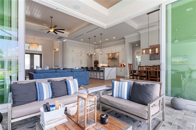 living room with a tray ceiling, ceiling fan, light hardwood / wood-style floors, and crown molding