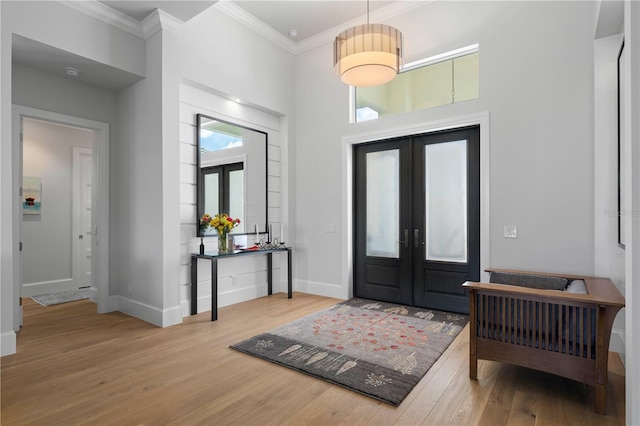 foyer entrance featuring light hardwood / wood-style floors, crown molding, and french doors