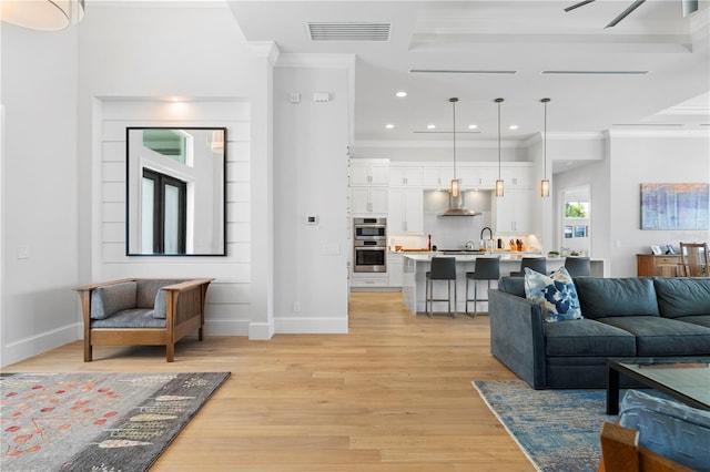 living room featuring light hardwood / wood-style flooring, ceiling fan, and ornamental molding