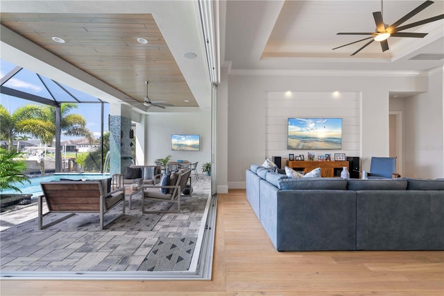 living room with a raised ceiling, ceiling fan, and light hardwood / wood-style floors