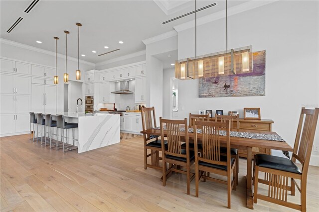 dining area featuring sink, light hardwood / wood-style floors, and ornamental molding