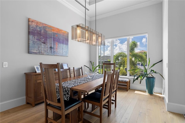 dining space featuring light wood-type flooring, ornamental molding, and a chandelier