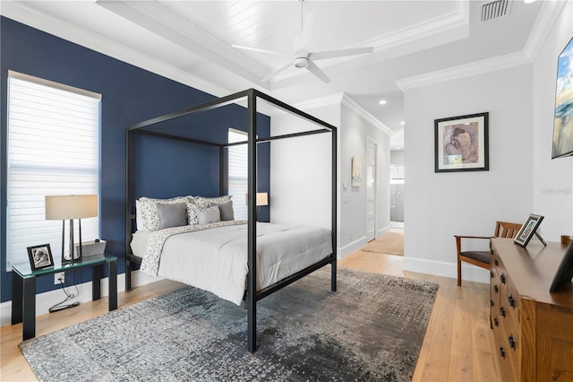 bedroom with light wood-type flooring, ceiling fan, a raised ceiling, and crown molding