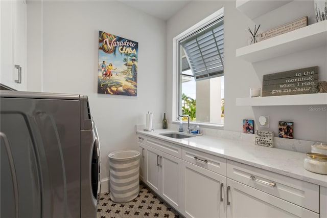 clothes washing area with washer / clothes dryer, cabinets, and sink