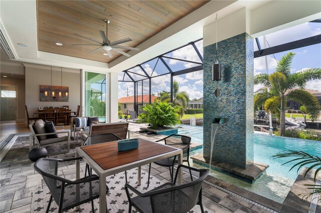 sunroom / solarium with ceiling fan, a tray ceiling, wooden ceiling, and a skylight