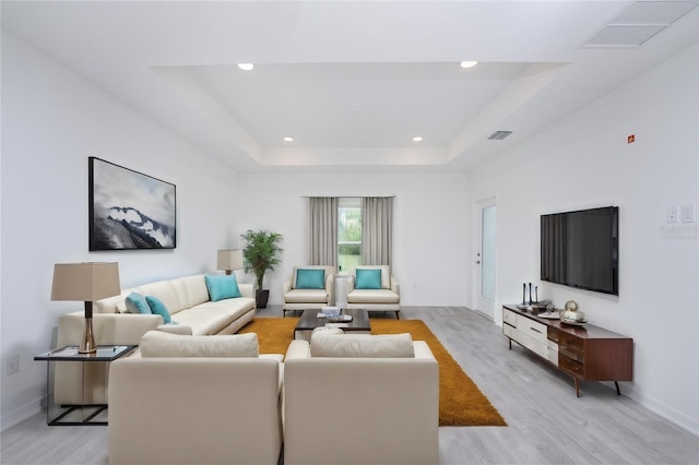 living room featuring light hardwood / wood-style floors and a raised ceiling