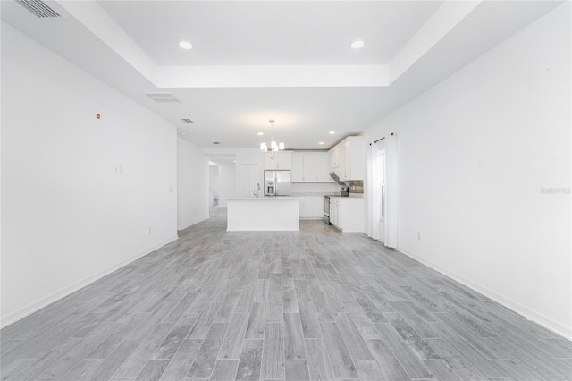 unfurnished living room featuring light wood-type flooring and an inviting chandelier