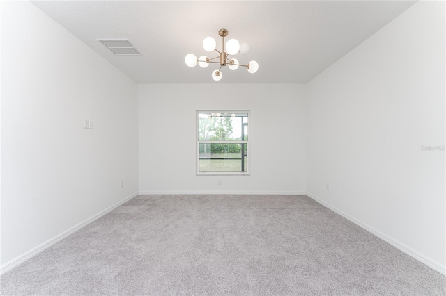 carpeted empty room with a chandelier