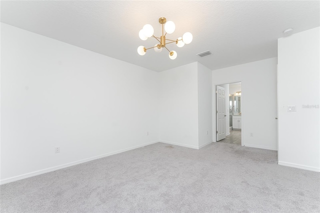 unfurnished room featuring a textured ceiling, light carpet, and a chandelier