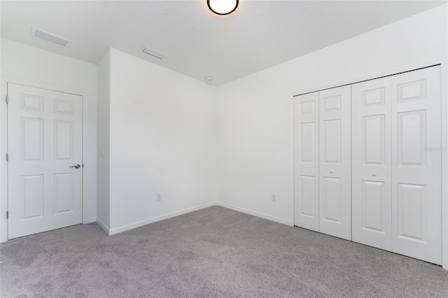 unfurnished bedroom with light carpet and a closet