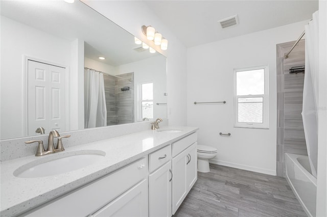 full bathroom with hardwood / wood-style floors, vanity, shower / tub combo with curtain, and toilet