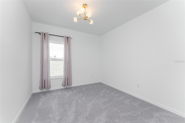 carpeted spare room with a chandelier