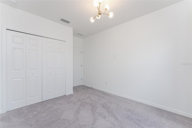 unfurnished bedroom with a chandelier, light carpet, and a closet