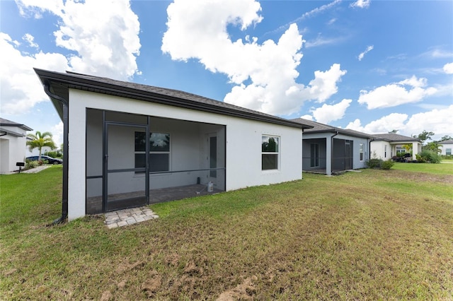 rear view of house featuring a lawn and a sunroom