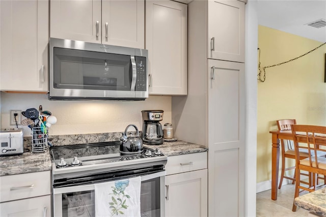 kitchen featuring light stone countertops, white cabinetry, and appliances with stainless steel finishes