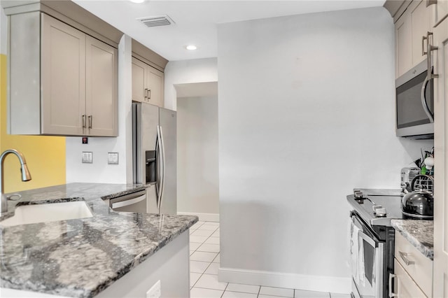 kitchen featuring stainless steel appliances, light stone countertops, sink, and light tile patterned floors