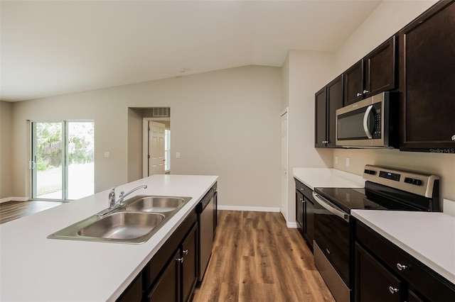 kitchen with dark brown cabinets, appliances with stainless steel finishes, light hardwood / wood-style floors, sink, and lofted ceiling