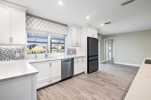 kitchen featuring light hardwood / wood-style floors, stainless steel dishwasher, sink, white cabinetry, and black fridge