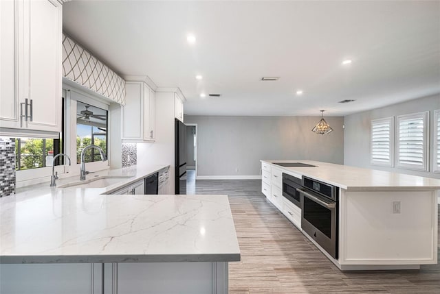 kitchen with black appliances, pendant lighting, light hardwood / wood-style floors, and white cabinets