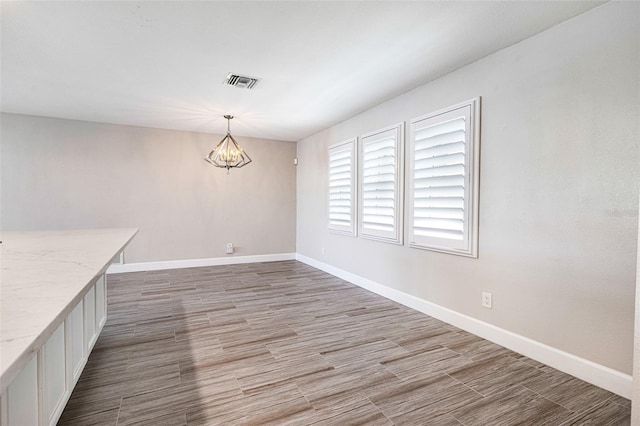 unfurnished dining area with hardwood / wood-style floors and an inviting chandelier