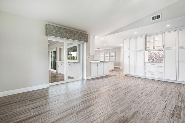 unfurnished living room featuring vaulted ceiling and light hardwood / wood-style floors