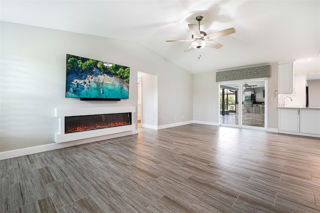 unfurnished living room featuring lofted ceiling, hardwood / wood-style flooring, and ceiling fan