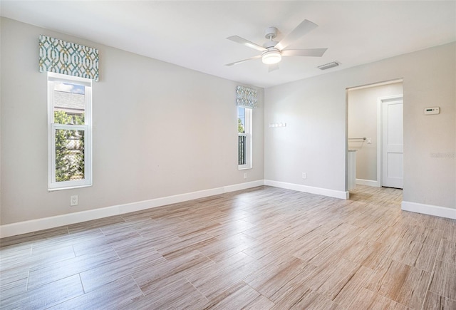 spare room with light wood-type flooring, plenty of natural light, and ceiling fan