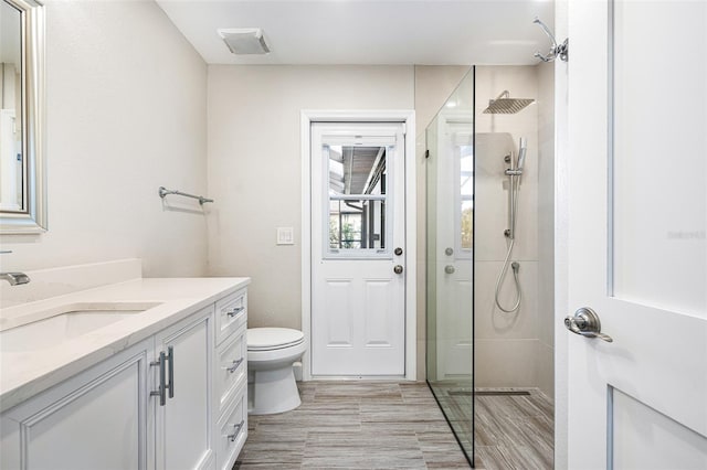 bathroom with a shower, toilet, hardwood / wood-style floors, and vanity