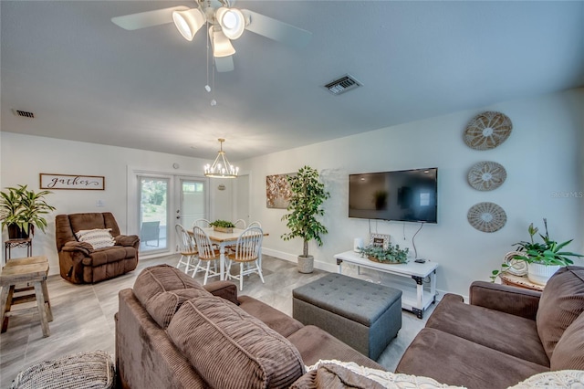 living room featuring french doors and ceiling fan with notable chandelier