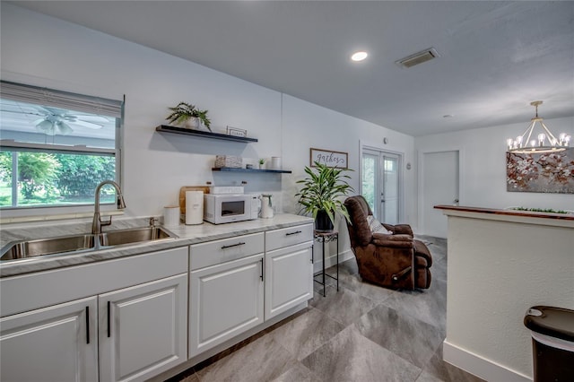 kitchen with a chandelier, pendant lighting, white cabinetry, and plenty of natural light