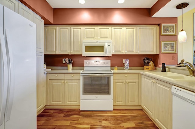 kitchen with pendant lighting, light wood-type flooring, white appliances, and sink