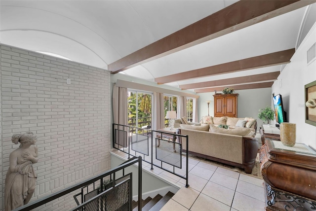 interior space with light tile patterned floors, brick wall, and beam ceiling