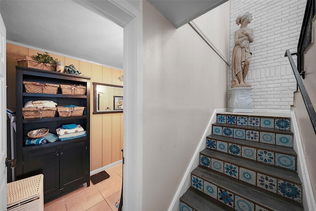 staircase featuring wood walls and tile patterned flooring