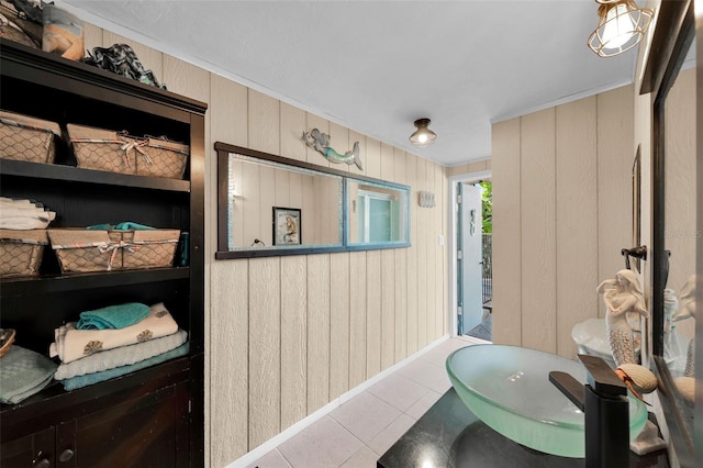 bathroom featuring tile patterned flooring, ornamental molding, and wooden walls