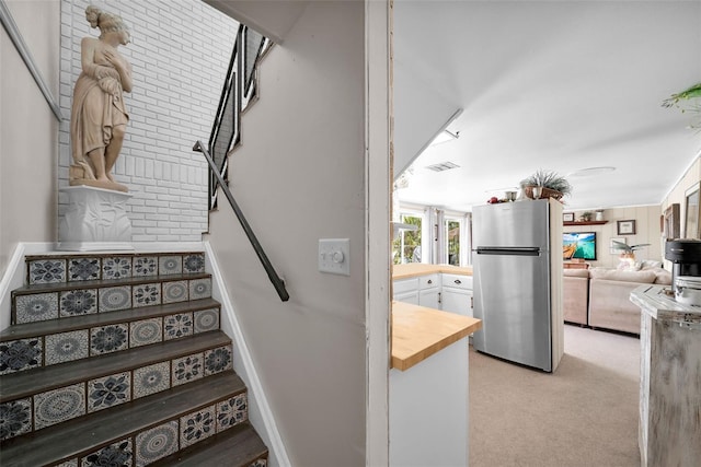 stairway with carpet and brick wall