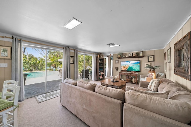 carpeted living room featuring wooden walls