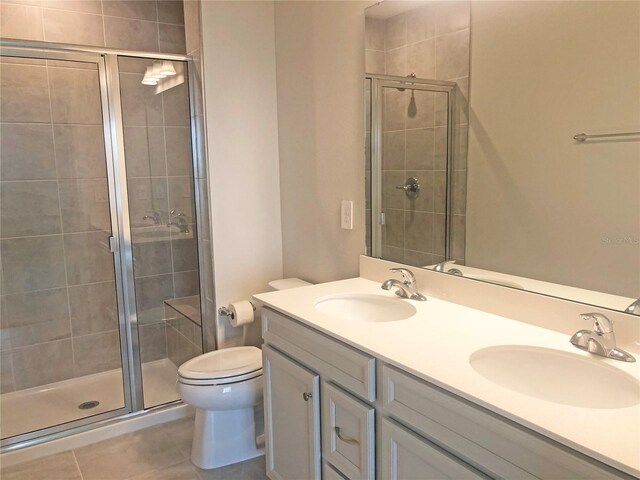 bathroom with tile patterned flooring, vanity, toilet, and walk in shower