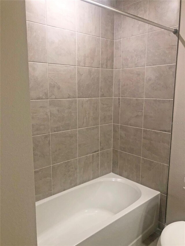 bathroom with tiled shower / bath and toilet