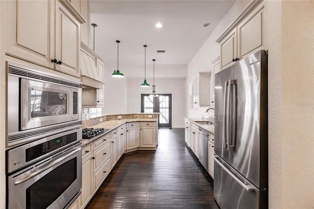 kitchen with decorative light fixtures, stainless steel appliances, dark hardwood / wood-style flooring, and light stone countertops