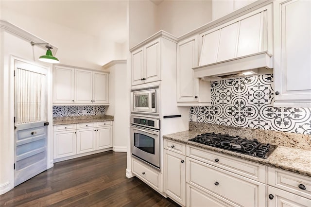 kitchen featuring light stone countertops, appliances with stainless steel finishes, backsplash, and dark hardwood / wood-style floors