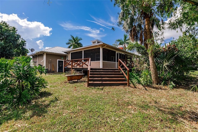 back of property with a deck, a sunroom, and a yard