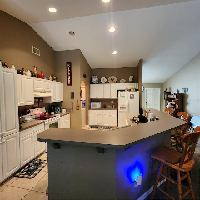 kitchen with a breakfast bar area, light tile patterned floors, white appliances, and white cabinets