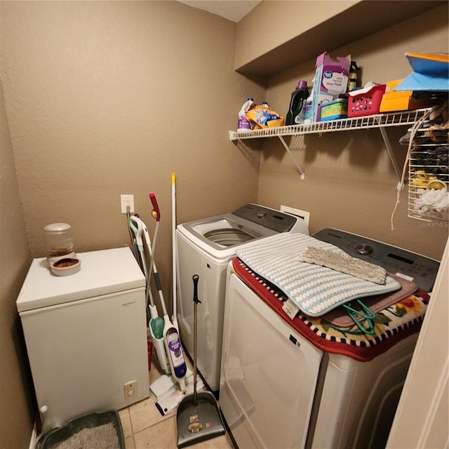 clothes washing area featuring light tile patterned floors and washer and dryer