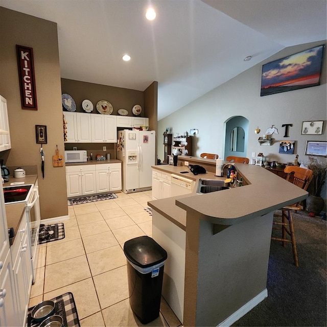 kitchen with vaulted ceiling, a breakfast bar area, white appliances, sink, and white cabinetry