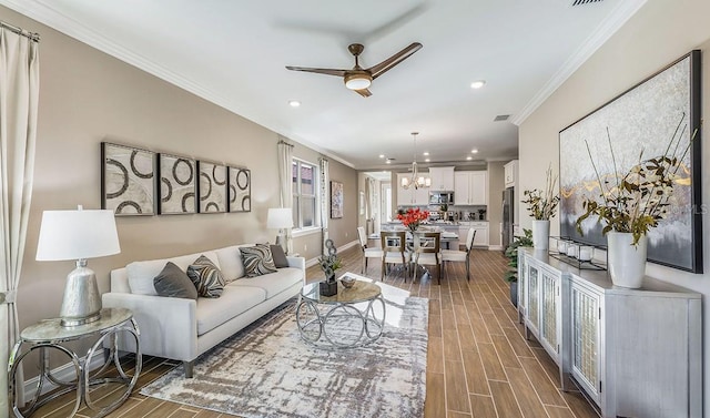 living room featuring crown molding and ceiling fan with notable chandelier