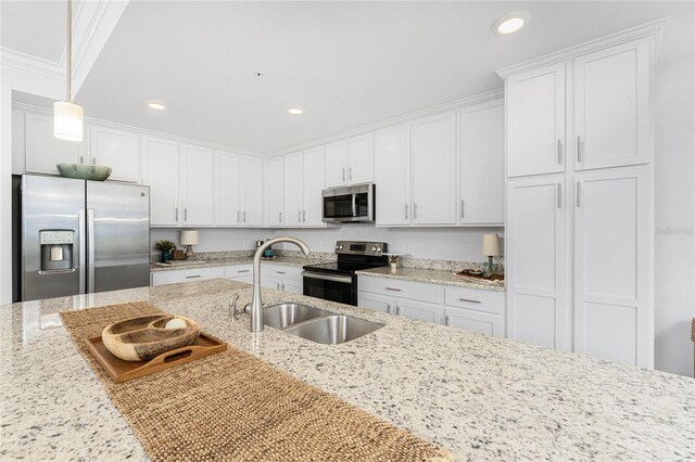 kitchen featuring crown molding, hanging light fixtures, stainless steel appliances, light stone counters, and white cabinets