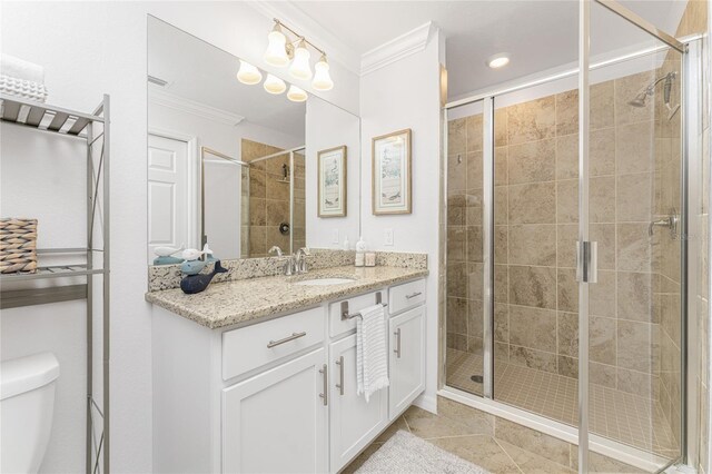 bathroom with vanity, a shower with shower door, tile patterned flooring, crown molding, and toilet