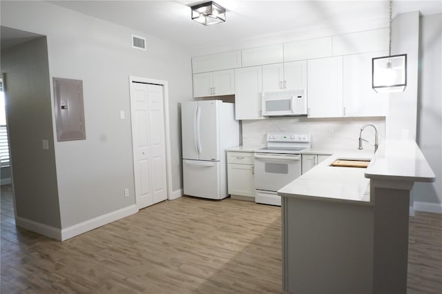 kitchen with white appliances, light hardwood / wood-style flooring, kitchen peninsula, sink, and white cabinets