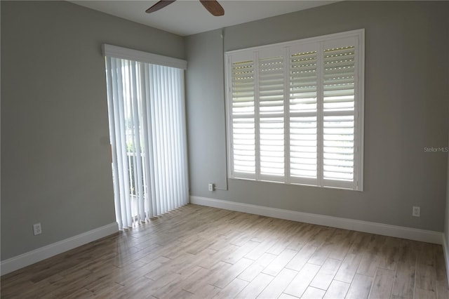 spare room featuring light wood-type flooring, a wealth of natural light, and ceiling fan